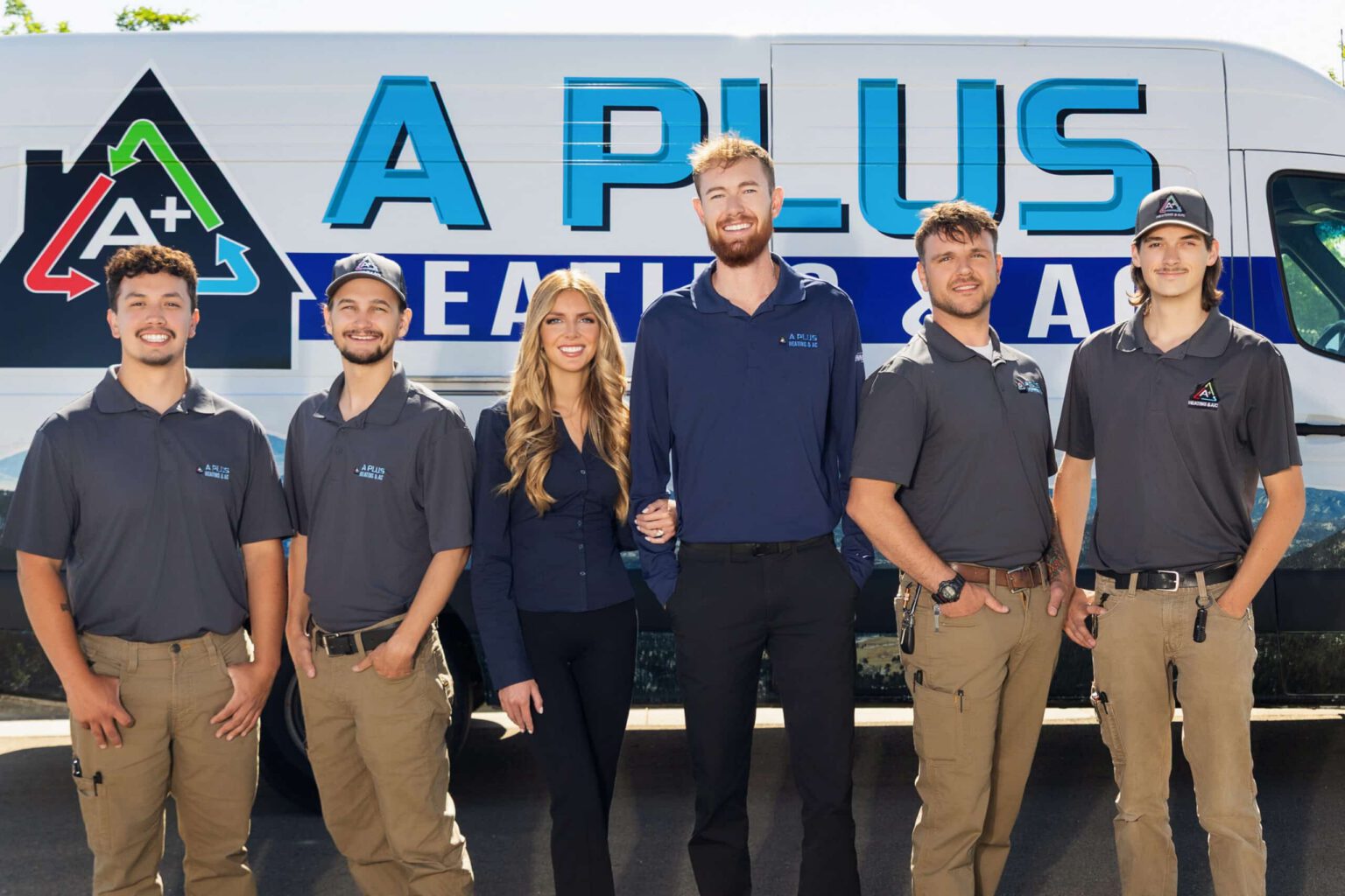 The A Plus Heating & AC team standing in front of a branded service van