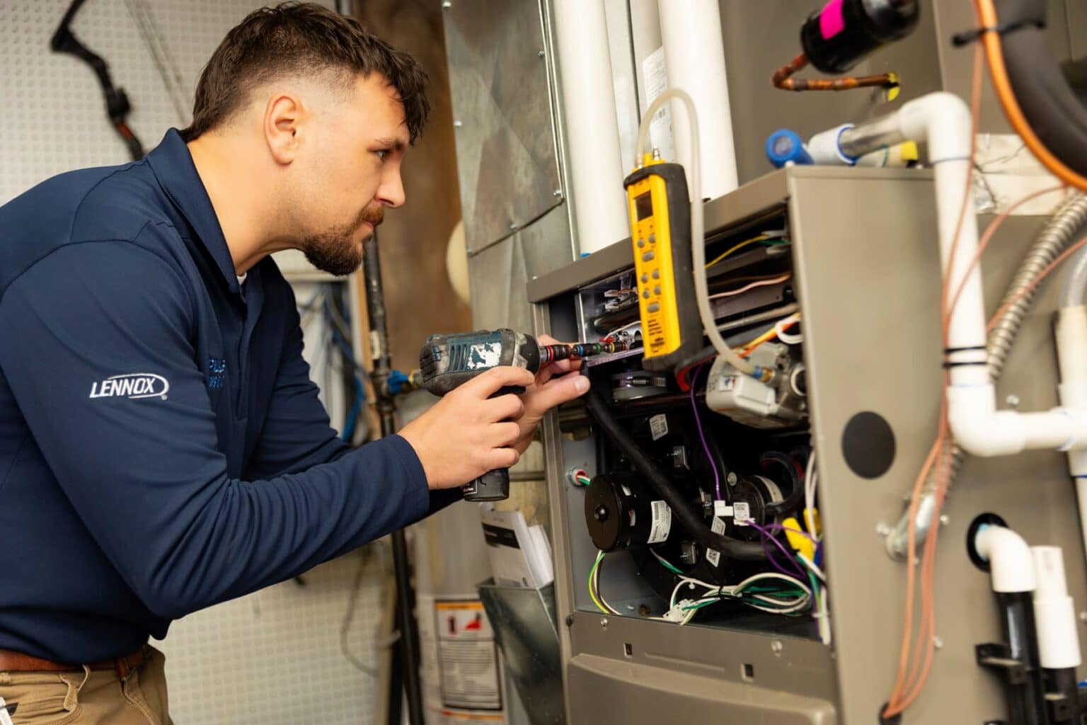 An A Plus technician testing the wiring on a home furnace